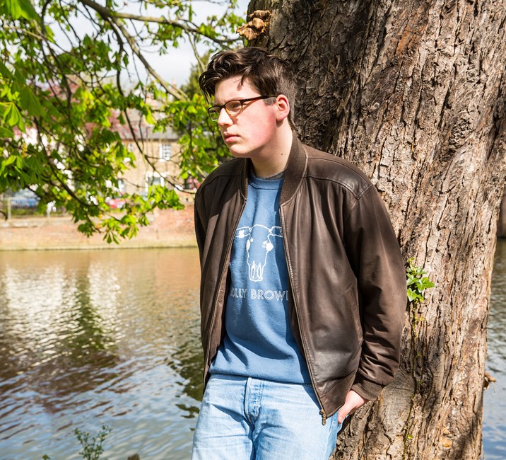 teenage boy leaning against a tree