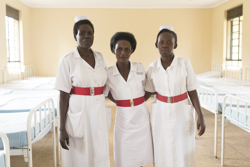three nurses looking at the camera standing in a hospital ward