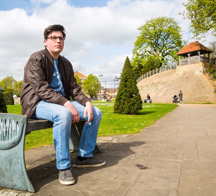 teenage boy sitting on a bench outside