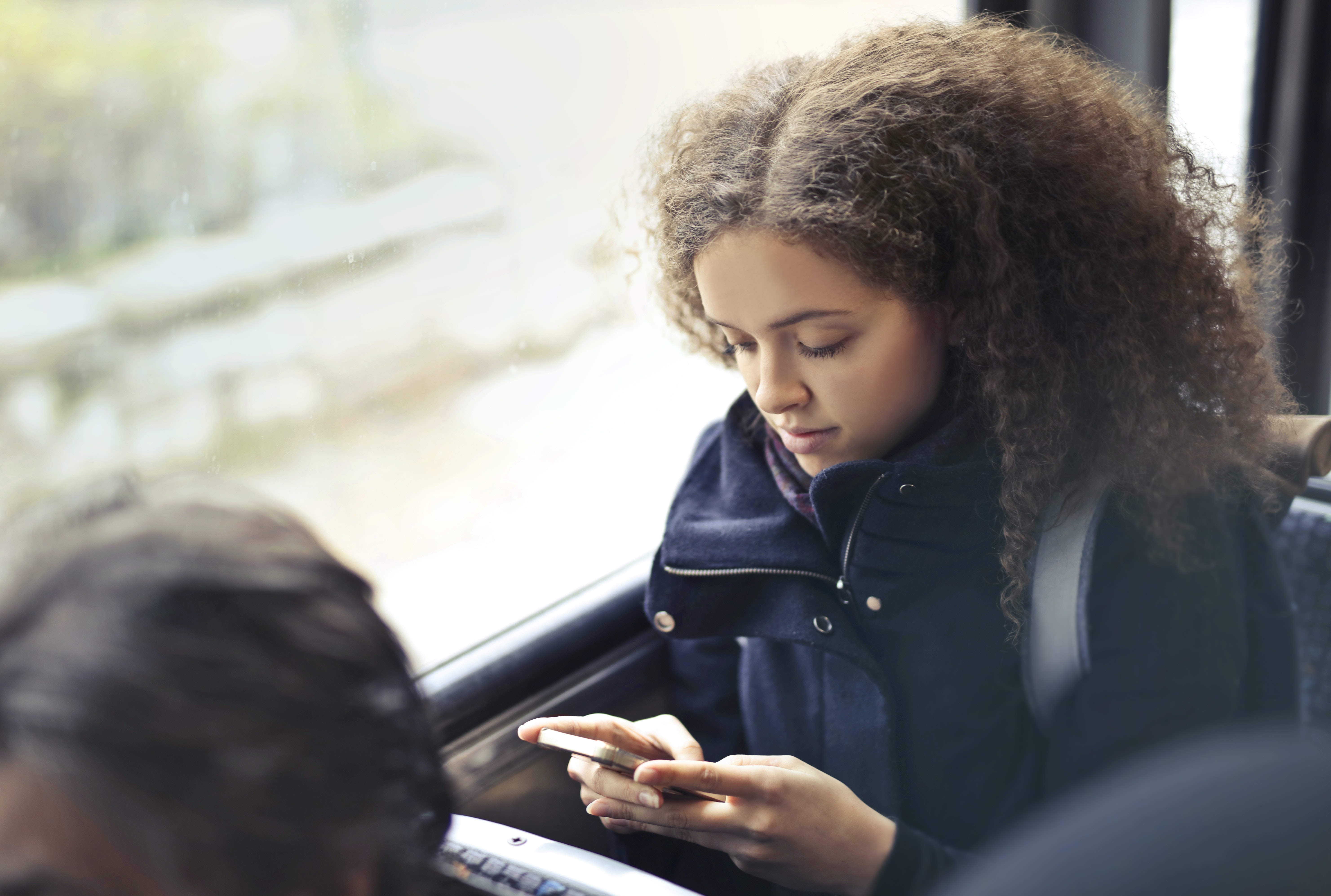Young Girl reading phone on bus