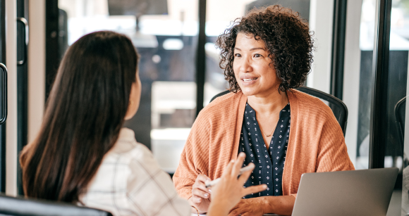 Two people talking at a desk