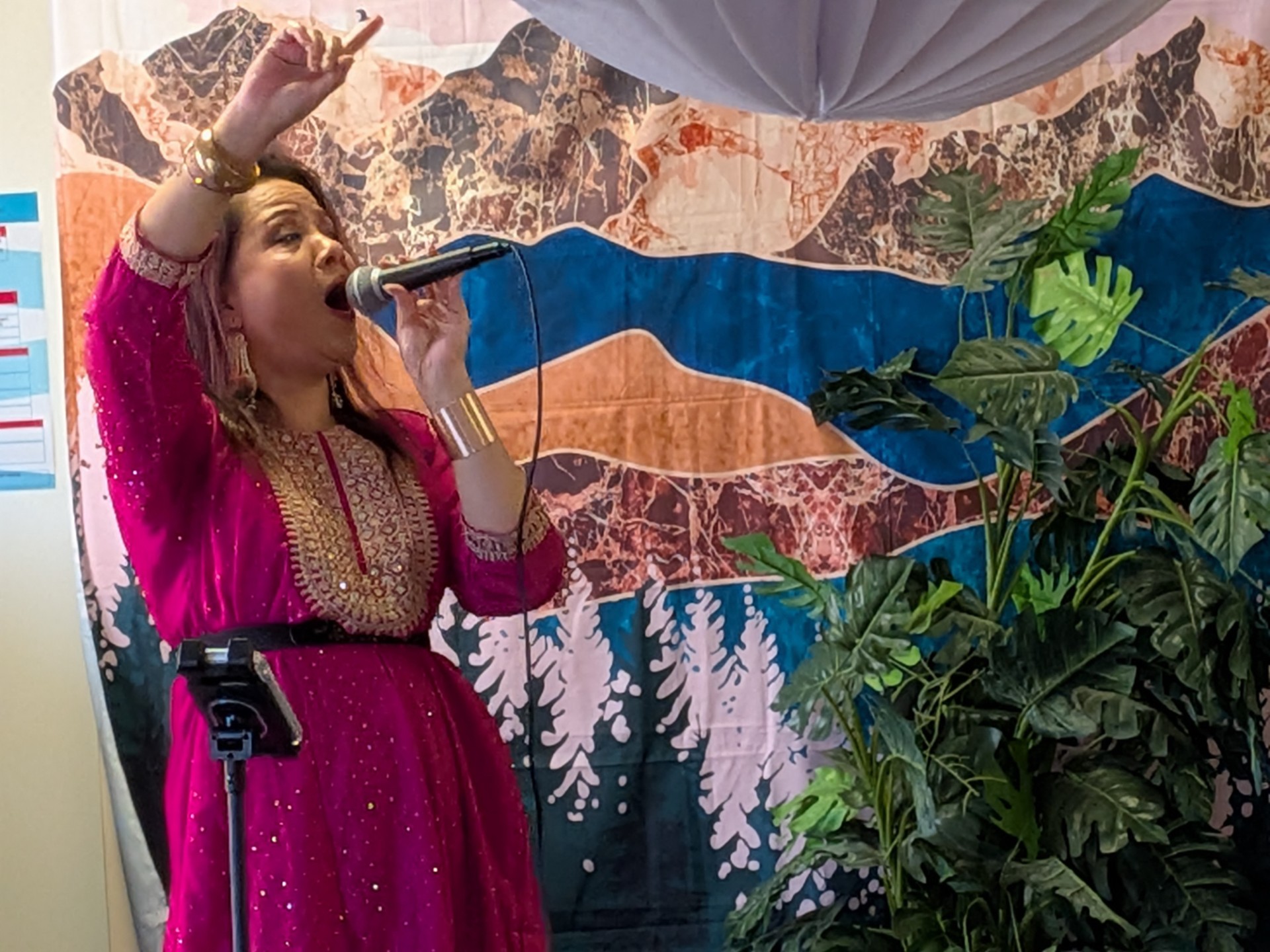 female in pink dress singng with arm in the air