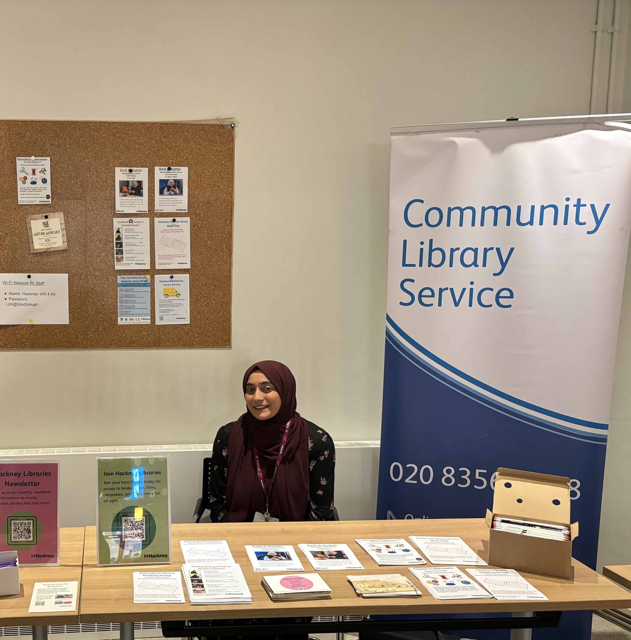 Library Officer sitting behind Hackney Community Library Service stall.
