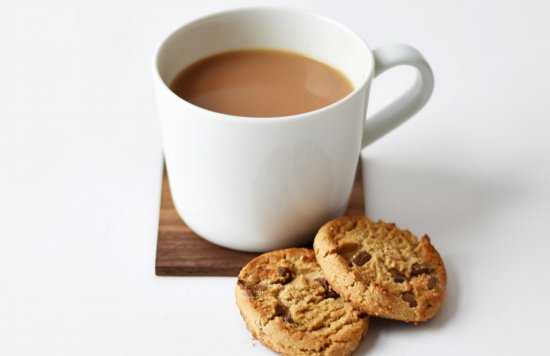 mug of tea with two chocolate chips cookies beside it