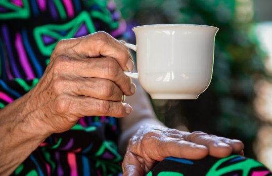 Hand of BAME older person holding a cup