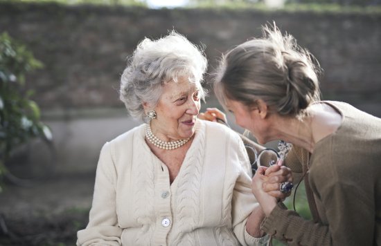 Older white female with grey hair talking with younger female