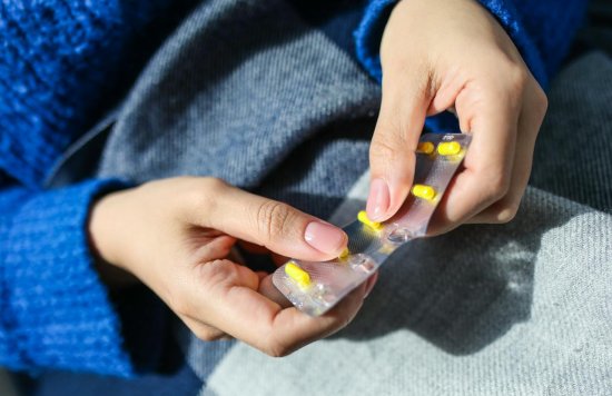Medication - hands popping yellow pill from blister pack