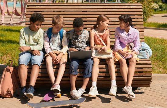 five diverse teens sitting on a bench