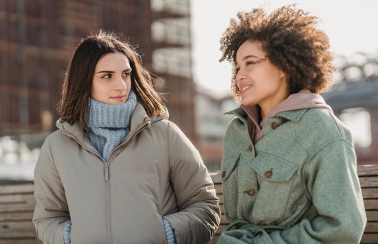 Stock image of two women talking to each other outside during winter.
