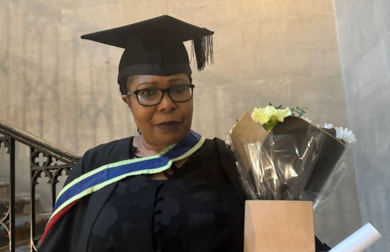 an image of Cornelia on her graduation day with her cap, gown and certificate