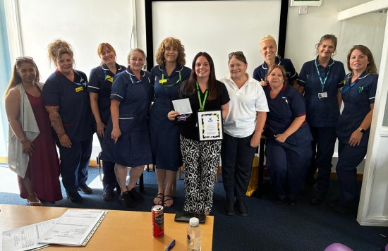 Sarah Myford standing with her award, next to colleagues.