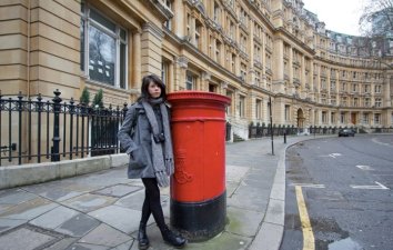 teenage girl standing next to a post box