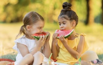 Two children eating watermelon in park