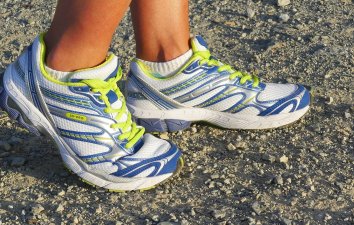Green and white trainers on gravel