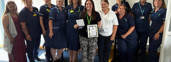 Sarah Myford standing with her award, next to colleagues.